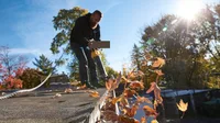 Technicien soufflant les feuilles d'automne hors d'une gouttière blanche