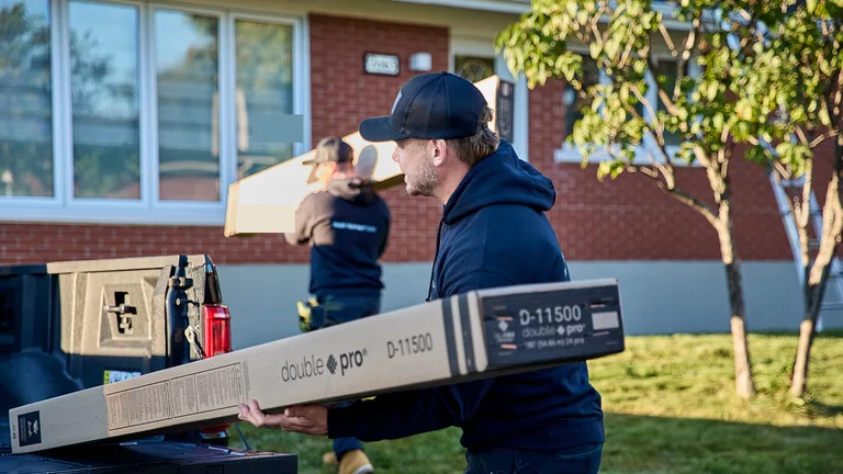 Installateurs déchargeant des boîtes DoublePro® Alu-Rex devant une maison de brique